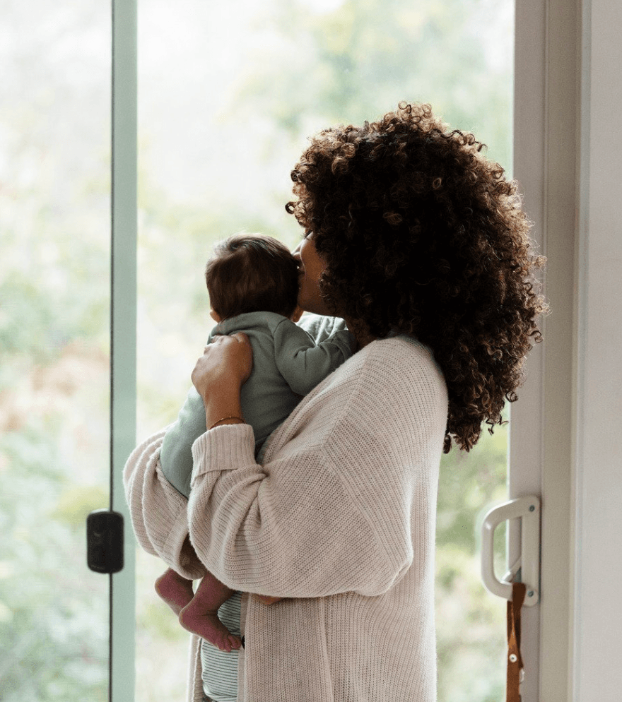mother holding young baby in front of a sliding glass door